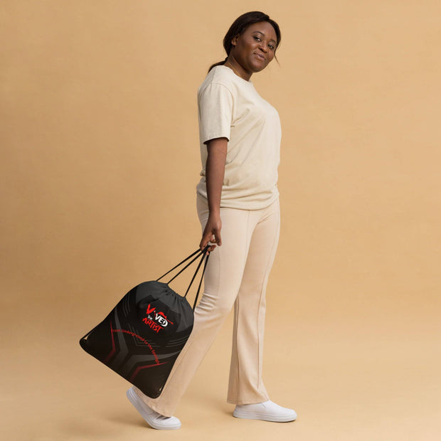 Viv'ed the Artist drawstring bag in black with red and gray accents, styled as a backpack, carried by a woman in beige athleisure wear.